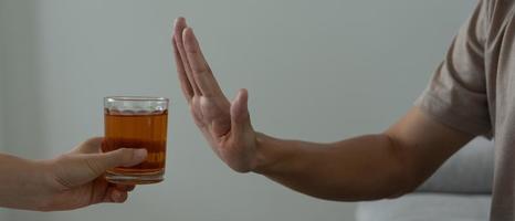 man refuses say no and avoid to drink an alcohol whiskey , stopping hand sign male, alcoholism treatment, alcohol addiction, quit booze, Stop Drinking Alcohol. Refuse Glass liquor, unhealthy, reject photo