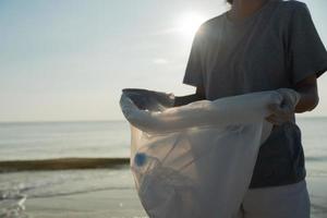 ahorrar agua. los voluntarios recogen basura en la playa y las botellas de plástico son difíciles de descomponer para evitar dañar la vida acuática. tierra, ambiente, planeta verde, reducir el calentamiento global, salvar el mundo foto