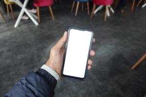 mano de hombre joven usando un teléfono inteligente con pantalla verde en el café foto