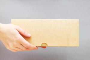 human hands holding delivers carton box on grey background. Delivery and online shopping concept. photo