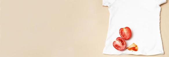 Tomatoes and ketchup stain on white shirt clothes on a beige background. banner photo