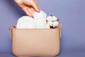 Women's hand takes out panty liner from pink cosmetic bag with tampons and feminine sanitary pads photo