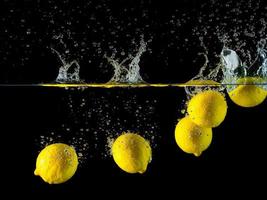 cinco limones son flotante en el claro agua tanque creando salpicaduras foto