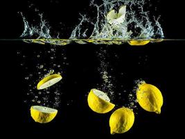 Lemons and lemon slices are dropped into the water creating massive splashes photo