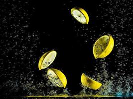 Lemons are falling into a tank with water creating water splashes slow motion photography photo