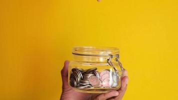 young man saving coins in a jar for property video