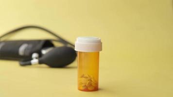 pill container and stethoscope on yellow background video