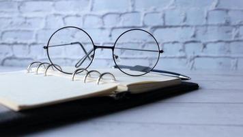 œil lunettes, ouvert livre et une crayon sur en bois table video