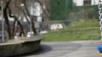 child having fun on a swing on the playground in public park. video