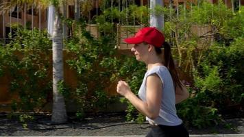 donna corre giù il strada tra il palma alberi. salutare attivo stile di vita video