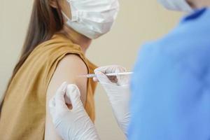 Covid-19,coronavirus hand of young woman nurse,doctor giving syringe vaccine, inject shot to asian arm's patient. Vaccination, immunization or disease prevention against flu or virus pandemic concept. photo