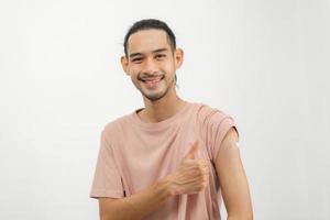 Portrait of asian young man, malel teenage attractive after getting, receive anti virus vaccine covid-19. Showing arm on bandage in casual, isolated on white background, copy space photo