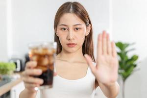 Diet asian young woman hand in  push out, deny sweet, sparkling water, suffering from toothache, sensitivity, inflammation when drink cold. Sensitive teeth, health weight loss people photo