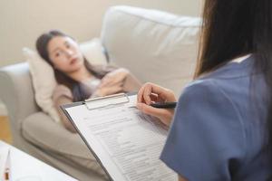 Psychology, depression. Sad, suffering asian young woman consulting with psychologist, psychiatrist while patient counseling mental with doctor woman taking notes at clinic. Encouraging, therapy. photo