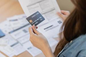 Financial owe asian young woman, girl sitting suffer, stressed and confused, hand in holding credit card, no money to pay expense, mortgage or loan. Debt, bankruptcy or bankruptcy concept. photo