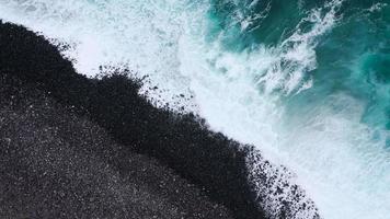 topp se av en folktom svart vulkanisk strand. kust av de ö av teneriffa. antenn Drönare antal fot av hav vågor nå Strand video