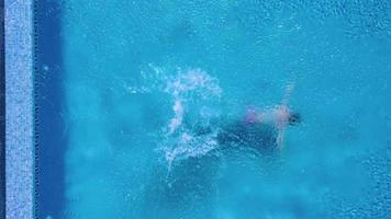 Aerial view of man in red shorts swims in the pool video