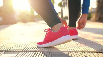 Close up of woman tying shoe laces and running along the palm avenue at sunset video