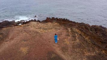 Aussicht von das Höhe von Frau im ein schön Blau Kleid und Hut steht auf oben von ein Berg im ein Erhaltung Bereich auf das Ufer von das atlantisch Ozean. Teneriffa, Kanarienvogel Inseln, Spanien video