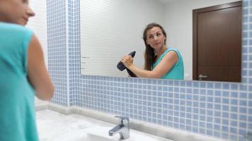 Söt kvinna avsätter och stil hår i främre av badrum spegel video