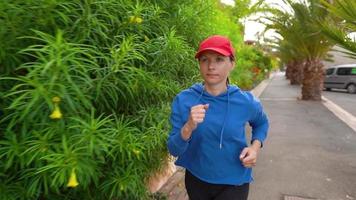 Woman jogging along the street among the tropical alley video