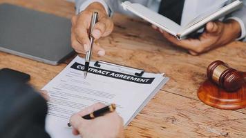 Business and lawyers discussing contract papers with brass scale on desk in office. Law, legal services, advice, justice and law concept picture with film grain effect video