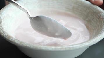 langzaam beweging van lepel plukken vers yoghurt in een kom Aan tafel video