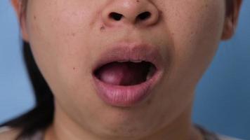 Young woman chewing gum and blowing bubble gum on blue background. video