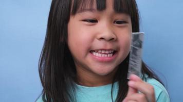 pequeño asiático niña cubierta su boca a oler el malo aliento. niño niña comprobación aliento con su manos. oral salud problemas o dental cuidado concepto. video