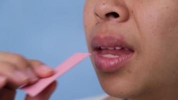 Young woman chewing gum and blowing bubble gum on blue background. video