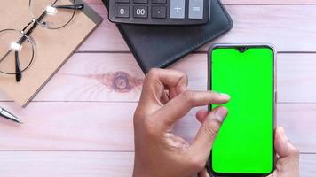 top view of smart phone with green screen and notepad on table video