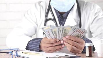 Doctor counting 100 us dollar cash on clinic desk video