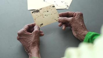 rear view of senior woman holding old photograph video