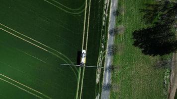Aerial top down view of combine spraying green field video