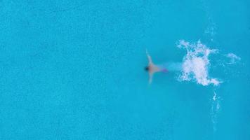 Aussicht von das oben wie ein Mann Springen und Tauchgänge in das Schwimmbad und schwimmt unter das Wasser video