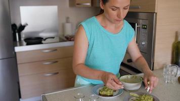 tempo periodo di cucinando avocado crostini - donna tagli il avocado e prende su il polpa, braciole esso e mette su pane, sale e spruzzatina con spezie. salutare vegano prima colazione video