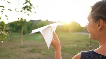 Woman launches paper airplane against sunset background. Concept of dreaming about traveling or the profession of a stewardess. video