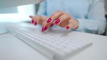 fêmea mãos com brilhante manicure digitando em uma computador teclado video