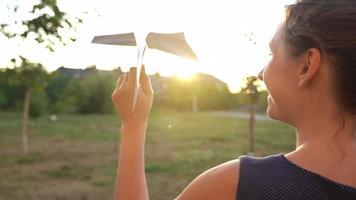 mujer lanza papel avión en contra puesta de sol antecedentes. concepto de soñando acerca de de viaje o el profesión de un azafata. video
