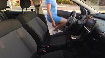 Woman in a blue dress sits in the car, fastens her seat belt and puts the key in the ignition before driving video