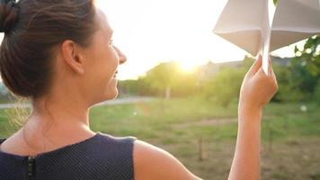 mulher lançamentos papel avião contra pôr do sol fundo. conceito do sonhando sobre viajando ou a profissão do uma comissária de bordo. video