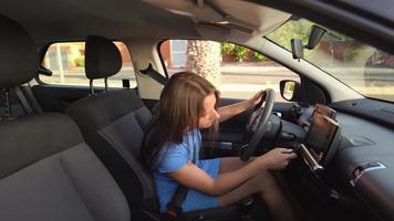 Woman in a blue dress sits in the car, fastens her seat belt and puts the key in the ignition before driving video