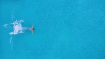 View from the top as a man jumping and dives into the pool and swims under the water video