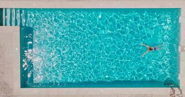 Aussicht von das oben wie ein Frau im ein Blau Badeanzug schwimmt im das Schwimmbad video