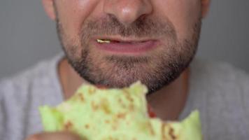 Man eating spinach shawarma with chicken and vegetables close-up video