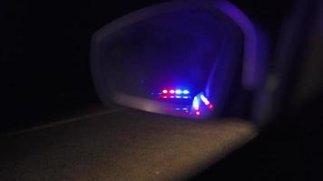 Flashing police lights reflected in the rearview mirror of a car at night video