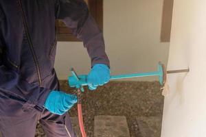 exterminate termite control company employee is using a termite sprayer at customer's house and searching for termite nests to eliminate. exterminate control worker spraying chemical insect repellant photo