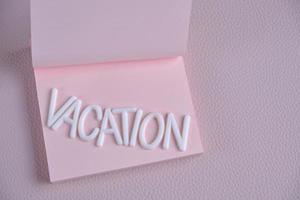 palabra vacaciones puesto fuera blanco letras rosado pedazo papel.concepto vacaciones, descanso y viajar. foto