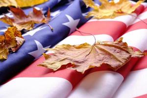 la bandera de los estados unidos de américa está cubierta de hojas de arce otoñales amarillentas. foto
