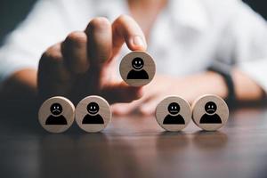 Customer service evaluation and satisfaction survey concepts. The client's hand picked the happy face smile face icon and five star symbol on wooden cube on table photo